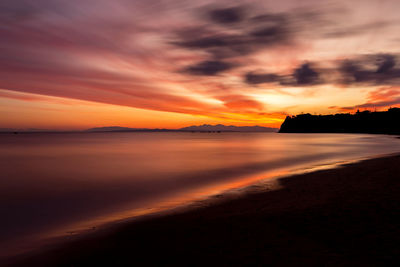 Scenic view of sea against dramatic sky during sunset