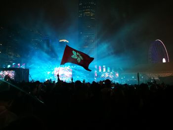 Crowd at music concert against sky at night