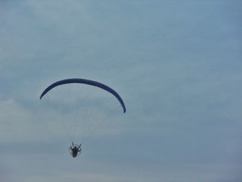 Low angle view of person paragliding against sky