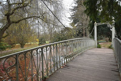 Footbridge amidst trees against sky