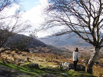 Rear view of woman walking on landscape against sky