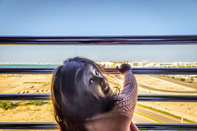 Horse looking away while standing by railing against sky