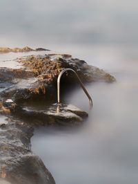 Close-up of rock in sea against sky