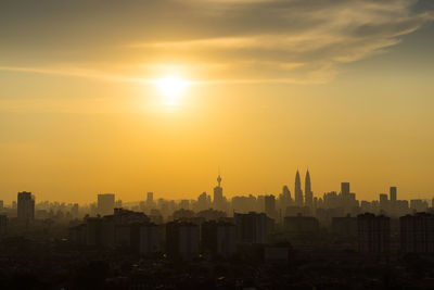 Buildings in city against orange sky during sunset