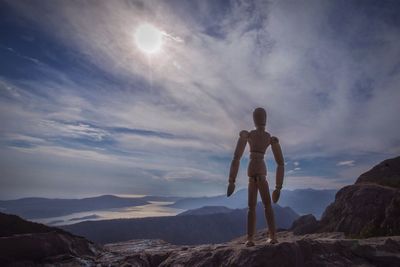 Low angle view of man standing on rock against sky