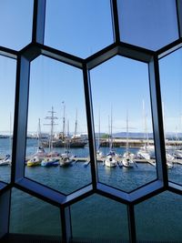 Sailboats in sea against clear blue sky seen through window