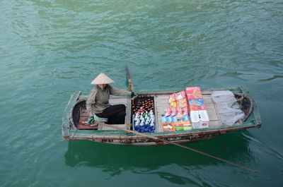 High angle view of woman selling food and drink on boat in river