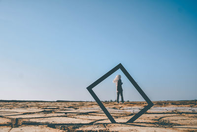 Woman standing on field against clear sky