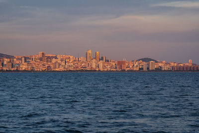 Sea by buildings against sky in city