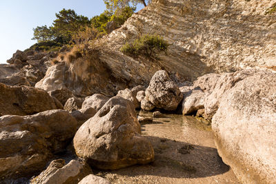 Large white stones in azure water against the background of rocks