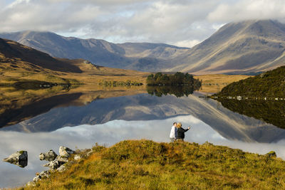 Man looking at lake against mountain range
