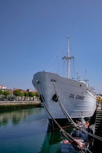 Sailboats moored in marina against clear blue sky