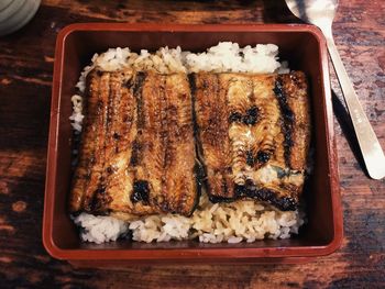 High angle view of cooked fish and rice in lunch box on table