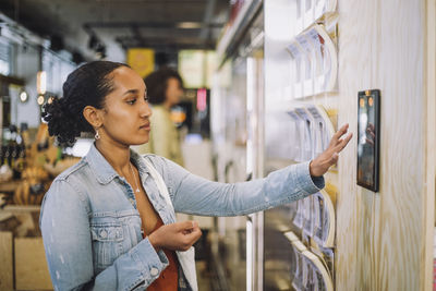 Female customer using digital tablet mounted on wall at grocery store