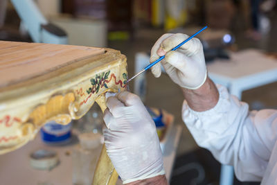 Cropped hand artist painting table at workshop