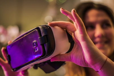 Woman holding virtual reality simulator in illuminated room