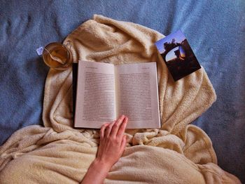 High angle view of man reading book on bed