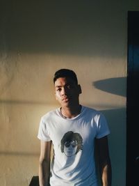 Portrait of young man standing against wall