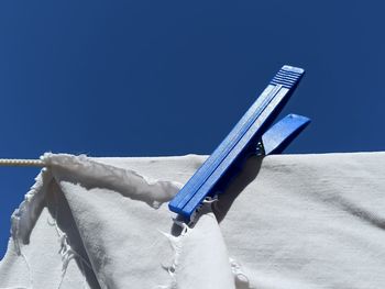 Close-up of clothes drying on clothesline against blue sky