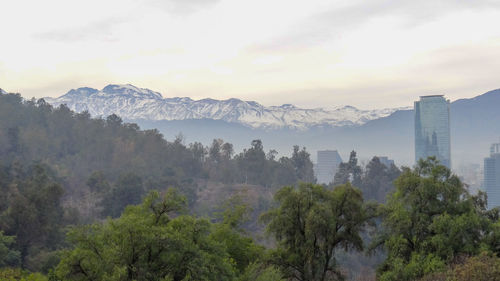 Scenic view of trees and buildings against mountain and sky