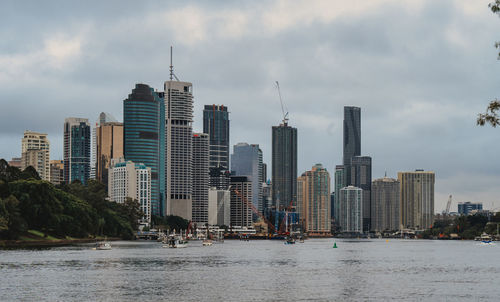 City at waterfront against cloudy sky