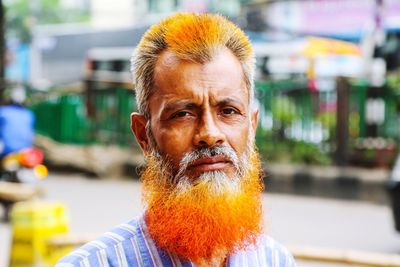 Close-up portrait of senior man with beard standing on road