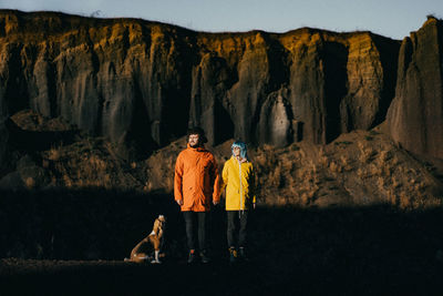 Rear view of man with dog walking on rock