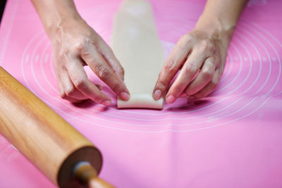 Woman's hands molding the rolle shape dough on pink silicone mesh