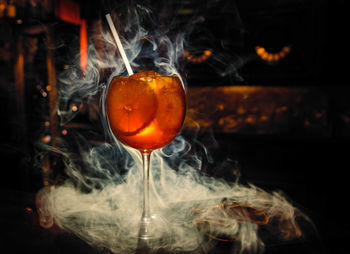 Close-up of wineglass amidst smoke on table