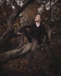 Mid adult man sitting on tree trunk in forest