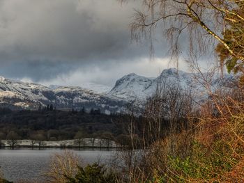 Scenic view of lake by snowcapped mountains against sky