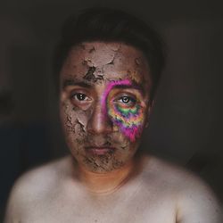 Portrait of shirtless young man with halloween make-up against black background