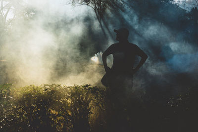Silhouette man standing amidst smoke in forest
