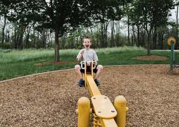 Portrait of happy boy playing on seesaw at park