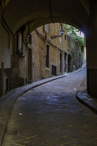 Wet street amidst buildings in city