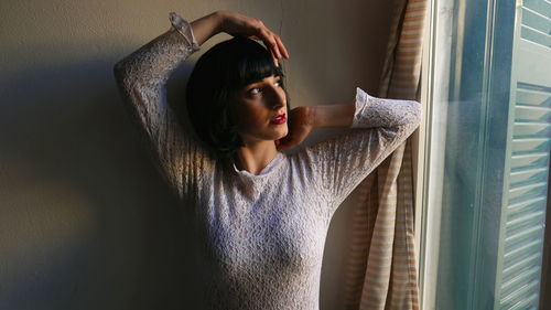 Woman looking through window at home