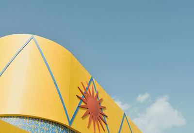 Low angle view of yellow umbrella against blue sky