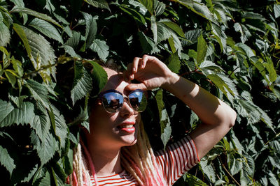 Young woman wearing sunglasses amidst plants