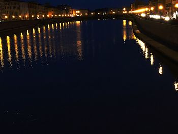 Illuminated bridge over river in city at night