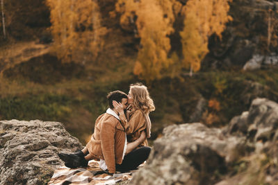 Rear view of people sitting on rock