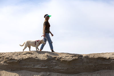 Young woman walking with her dog on the sand in desert