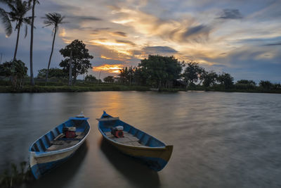 Boat moored at shore against sky during sunset