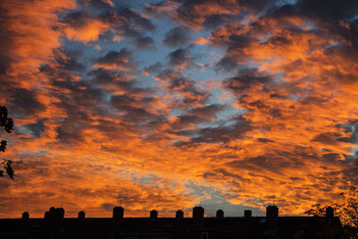 Silhouette buildings against dramatic sky during sunset