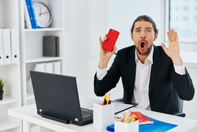 Businessman shouting on phone at office