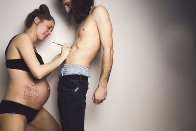 Man with pregnant woman standing against gray background