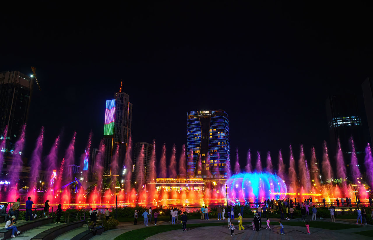 night, illuminated, architecture, city, crowd, building exterior, built structure, group of people, large group of people, travel destinations, sky, celebration, motion, event, nature, outdoors, arts culture and entertainment, lighting equipment, multi colored, light, skyline, lighting, street, travel, skyscraper, city life