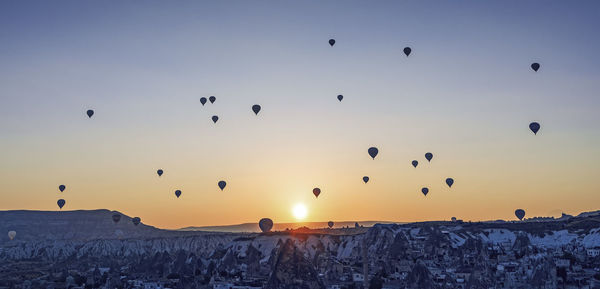 Silhouette of hot air balloons against sky during sunset