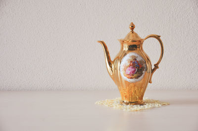 Close-up of teapot on table against wall