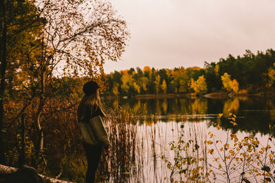 Rear view of woman standing by lake against sky