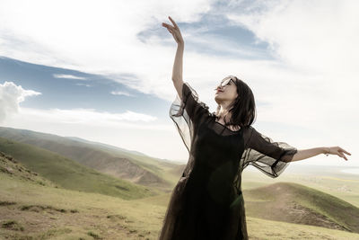 Young woman standing on landscape against sky